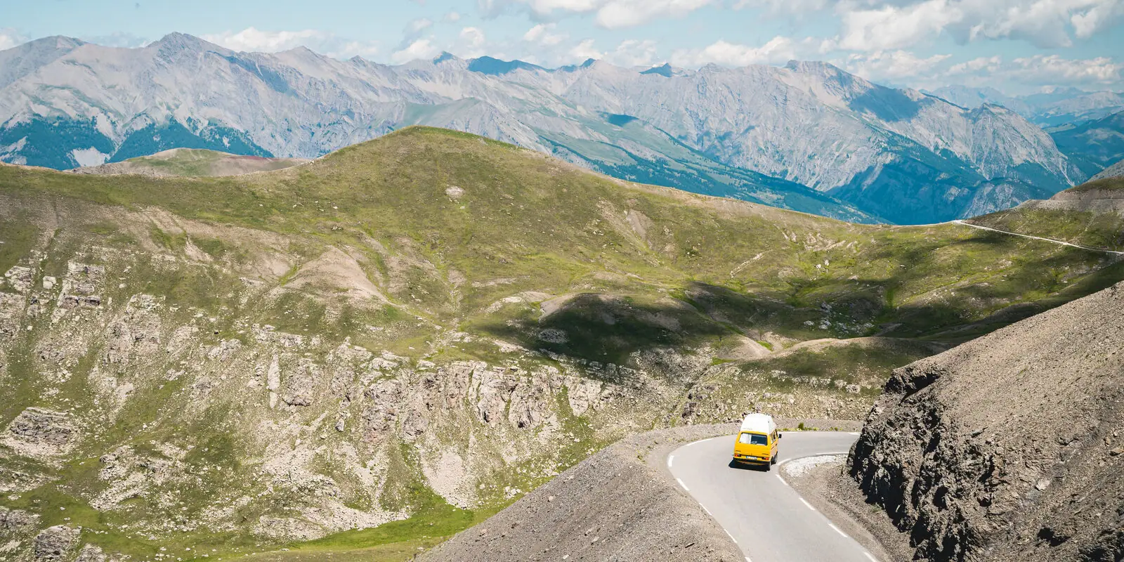 Van on a mountain road through a dry alpine valley