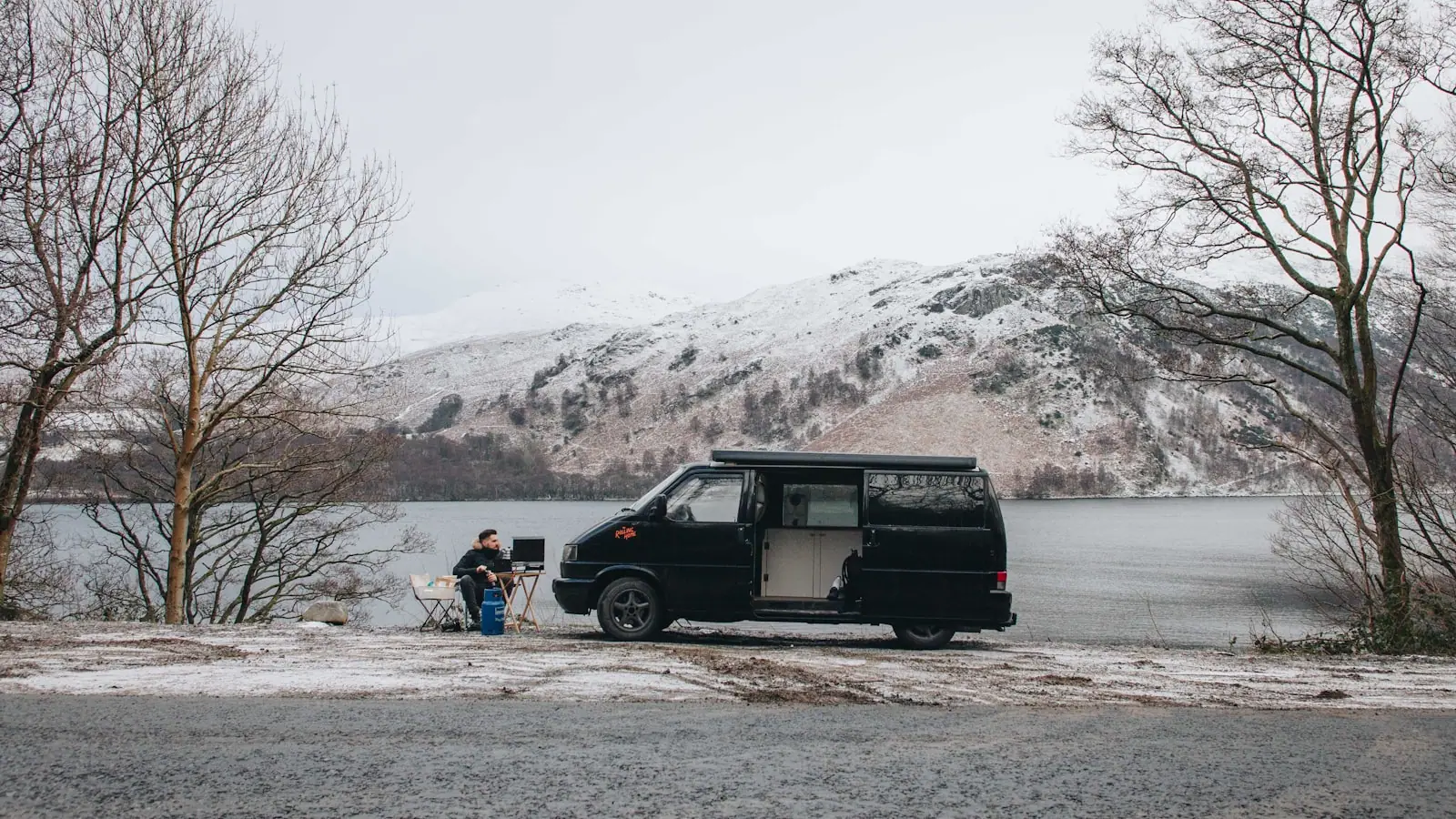 Campervan parked by a lake in the mountains at dawn