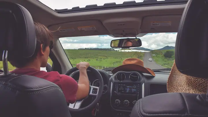 Parent settling a baby into a car before a trip