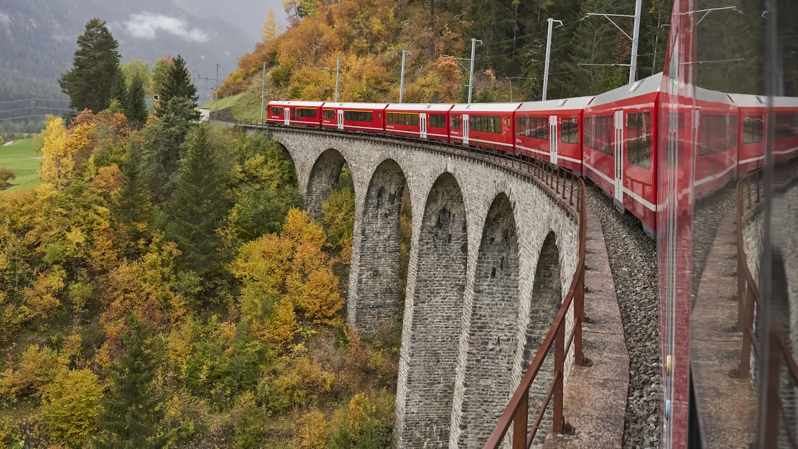 Red Swiss train crossing a viaduct in the Alps